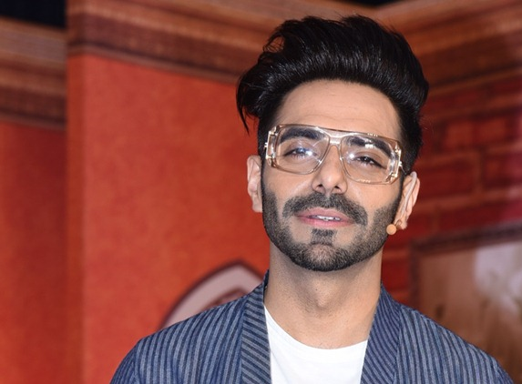 Aparshakti Khurana Wiki - A stunning picture of Aparshakti wearing spectacles in a check blue outfit.